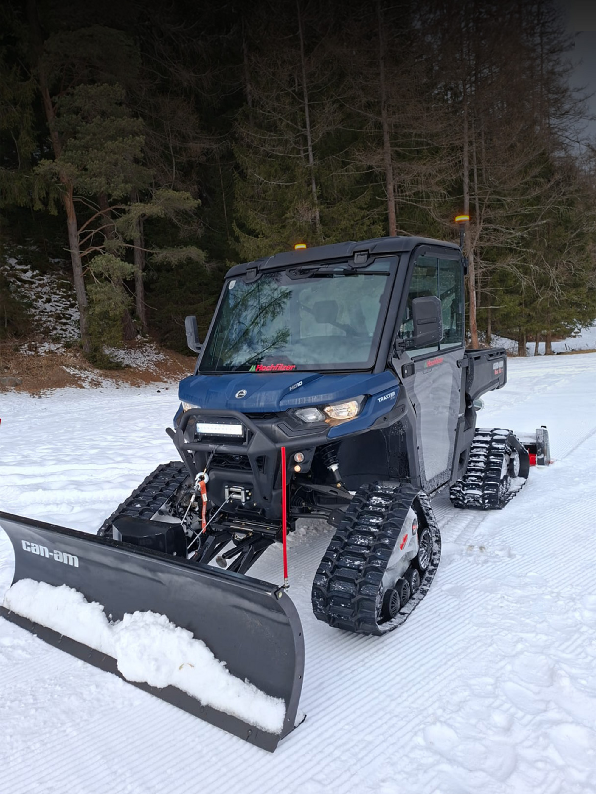 Für perfekt präparierte Wege Can-Am Side-by-Side Fahrzeug mit Trailmaster 180 und Schneeräumschild in winterlicher Kulisse.
