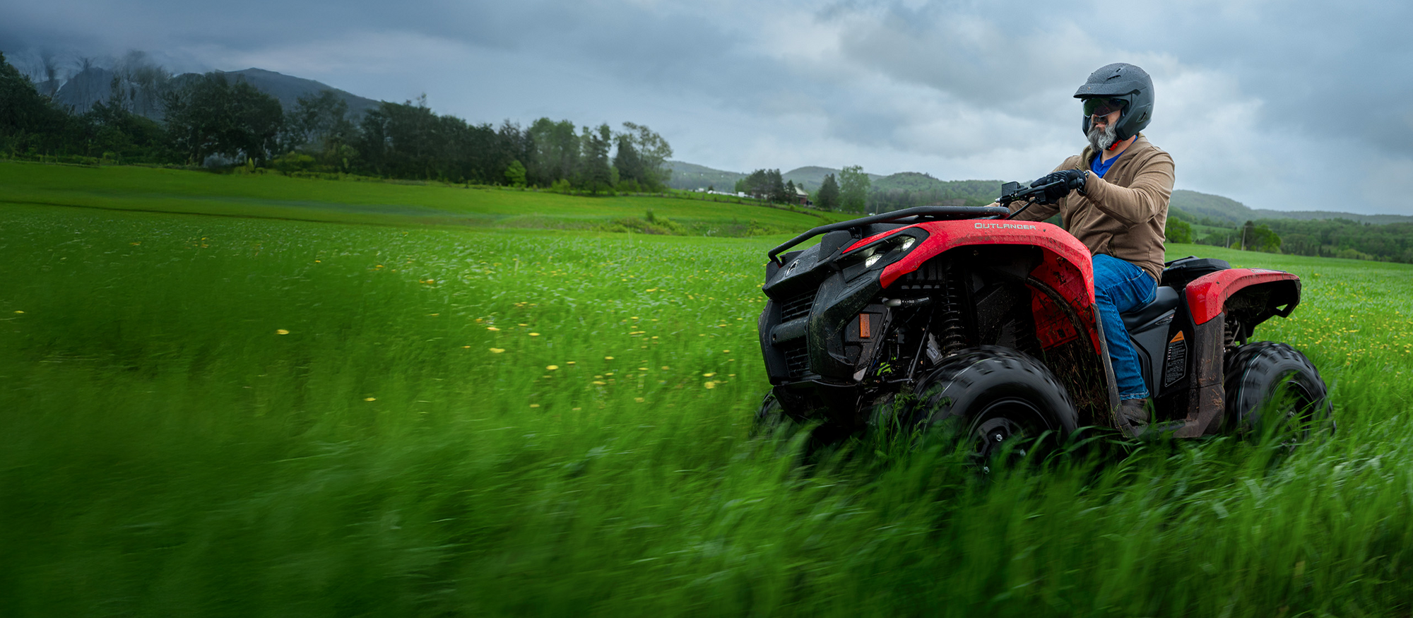 Mann fährt mit ATV über eine Wiese.